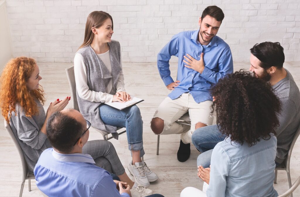 Cheerful man appreciates support of people at rehab group meeting